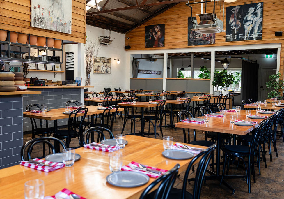 Long wooden tables inside The Independent Gembrook, with the bar seen in the background.